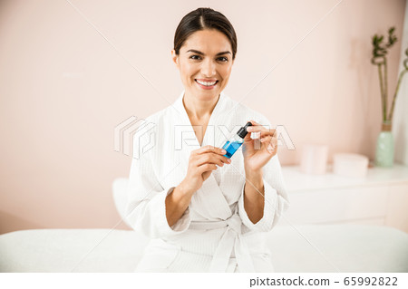 Happy pretty woman with anti-age serum in hands Happy pretty woman with anti-age serum in hands 65992822