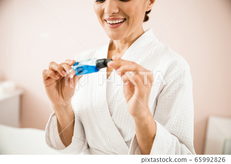 Smiling pretty woman holding bottle with cosmetic Smiling pretty woman holding bottle with cosmetic 65992826