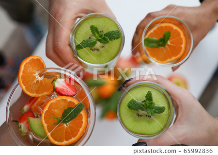 People holding glasses with bright fruit drinks 65992836