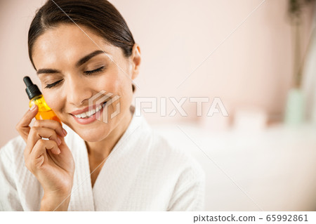 Happy attractive woman with cosmetic drops in hand Happy attractive woman with cosmetic drops in hand 65992861