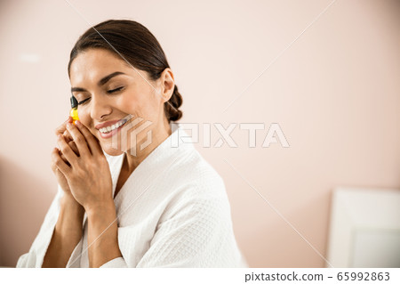 Smiling beautiful woman hugging cosmetic treatment with gratitude 65992863