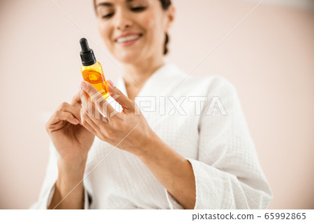 Happy female applying drops for skin care Happy female applying drops for skin care 65992865