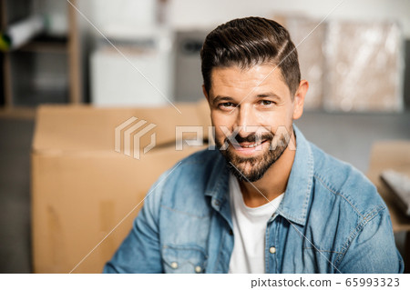 Joyful bearded man near carton boxes in empty apartment 65993323