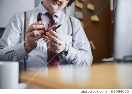 Male office employee of older generation with stapler 65994000