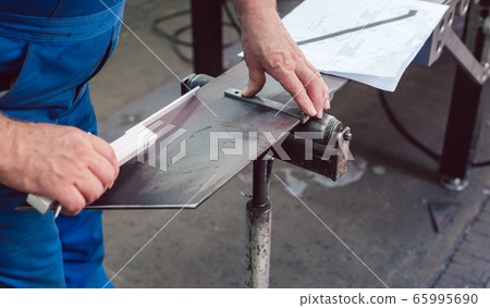 Metalworker measuring a strip of steel 65995690