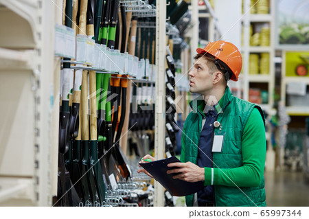 warehouse worker counts the number of shovels in store 65997344