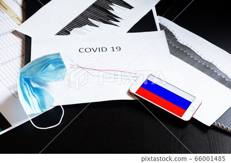 End of pandemic coronavirus and isolation. Used crumpled medical mask and mobile with flag of Russia on chart for reducing the incidence of morbidity and mortality. Selective focus 66001485