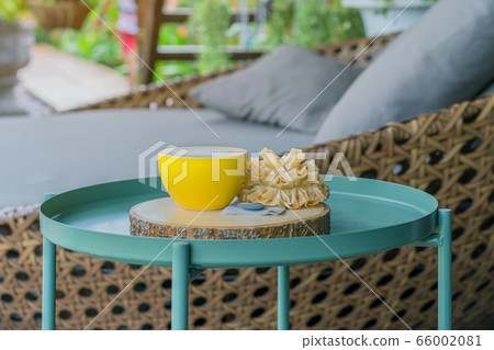 Hot coffee in a yellow cup and crispy lotus blossom cookie for relax time on wooden board at the balcony 66002081