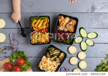 girl holds spoon to eat ready meal into food containers, raw vegetables for health, top view girl holds spoon to eat ready meal into food containers, raw vegetables for health, top view 66002284