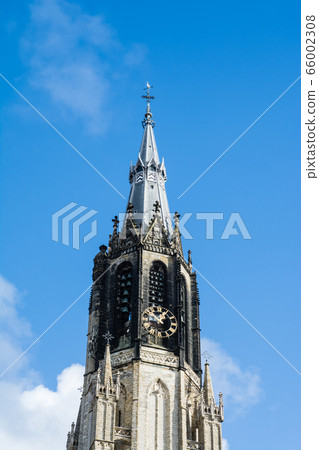 Towers of the historic brick tall tower of Delft in the Netherlands towering under the blue sky and clouds 66002308