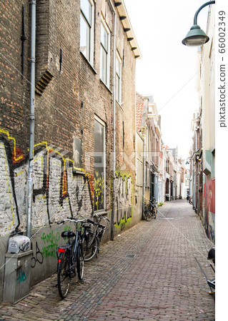 Cityscape of Delft in the Netherlands Cobblestone path between brick buildings 66002349
