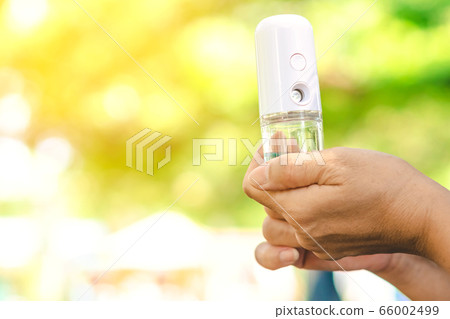 Woman using alcohol nano mist sprayer antiseptic cleaning on her hands protection during Coronavirus pandemic Covid-19.Hand using sanitizer spray.Modern health technology concept.New normal lifestyle. 66002499