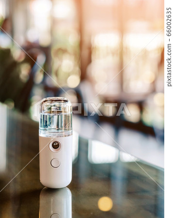 Alcohol nano mist sprayer for hand cleaning to prevent the spread of the corona virus (Covid-19) placed on the table to serve customers before buying in the coffee shop. Modern health technology. 66002635