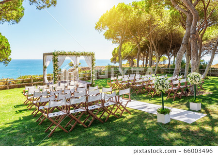 Beautiful wedding by the ocean on a sunny day. Arch cleaned with flowers. Beautiful wedding by the ocean on a sunny day. Arch cleaned with flowers. 66003496