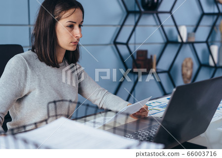 Woman sitting in office and working on laptop 66003716