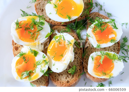 Soft-boiled egg halves with dill on whole grain toast bread on a white plate. Close-up, top view Soft-boiled egg halves with dill on whole grain toast bread on a white plate. Close-up, top view 66006509