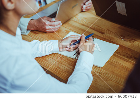 Woman preparing to write in notebook. Woman holds pen and open notebook is ready to write down ideas while discussing new project. Planning concept. Business meeting concept. Close up of female hands 66007418