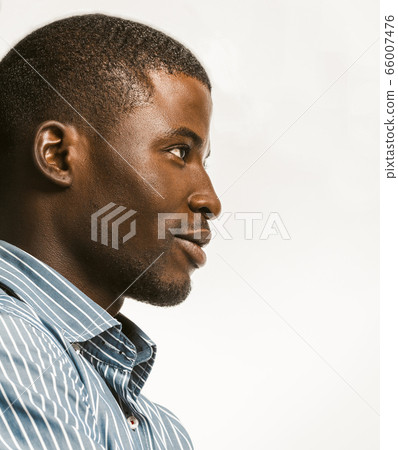 Confidently African American man delicately smiling looking at right side with textspace. Young dark-skinned businessman isolated on white background. Profile view. Close up bottom shot. Toned image 66007476