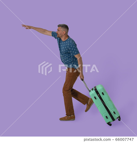 Caucasian man carries plastic suitcase with luggage on wheels holding it by handle. Traveler held out his hand trying to catch taxi cut out on colored background. Advertising template with copy space Caucasian man carries plastic suitcase with luggage on wheels holding it by handle. Traveler held out his hand trying to catch taxi cut out on colored background. Advertising template with copy space 66007747