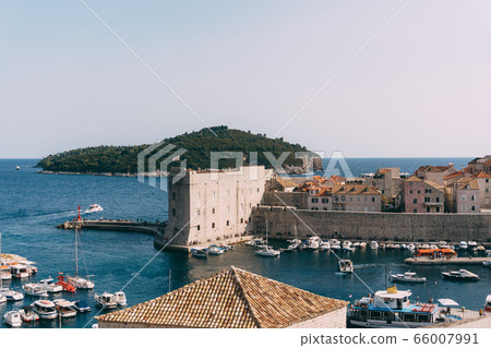 The old port harbor is porporela, near the walls of the old town of Dubrovnik, Croatia. View of the fort on the wall, Lokrum island and moored boats near the city walls. 66007991