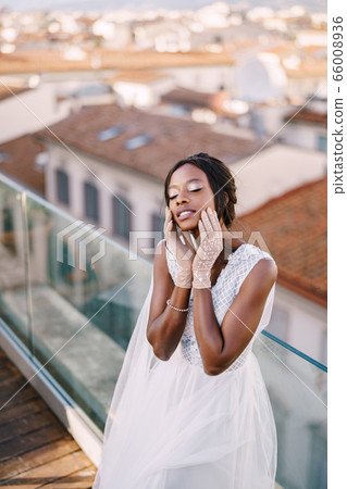 Beautiful African American bride in a white wedding dress, touches her face in vintage gloves. Fine-Art Wedding in Florence, Italy. Beautiful African American bride in a white wedding dress, touches her face in vintage gloves. Fine-Art Wedding in Florence, Italy. 66008936