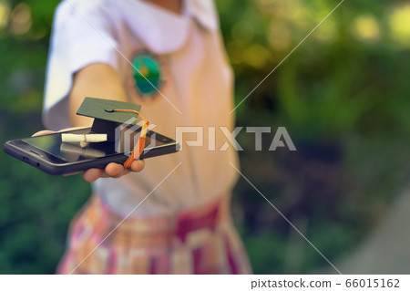 Online e-learning and graduate certificate program concept : Hands of schoolgirl with smartphones and graduation hat. Depicts distance learning online education can be done via internet Online e-learning and graduate certificate program concept : Hands of schoolgirl with smartphones and graduation hat. Depicts distance learning online education can be done via internet 66015162