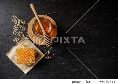 Honey bee and Honeycomb with honey dipper and dry flower on black background, bee products by organic natural ingredients concept 66019234