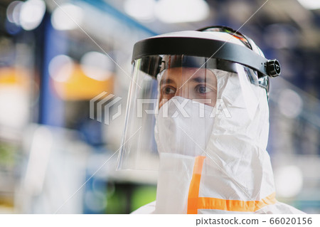 Close-up portrait of worker with protective mask and suit in industrial factory. 66020156