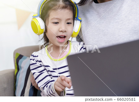 Asian little child girl learning at home with laptop computer using meeting online app with her mother, Quarantine isolation during the Coronavirus (COVID-19) health care, online education concept Asian little child girl learning at home with laptop computer using meeting online app with her mother, Quarantine isolation during the Coronavirus (COVID-19) health care, online education concept 66020581