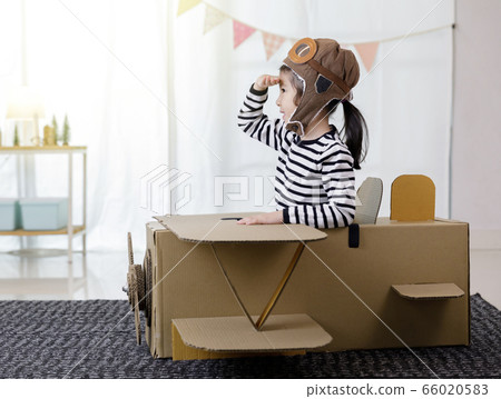 Asian little child girl playing with cardboard toy airplane handicraft isolated in home with copy space for your text, Creative with family and dreaming of flying concept 66020583