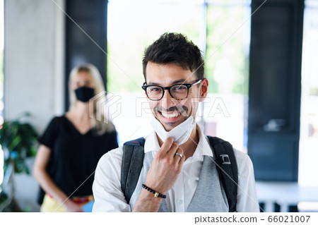 Portrait of young man with face mask back at work in office after lockdown. 66021007
