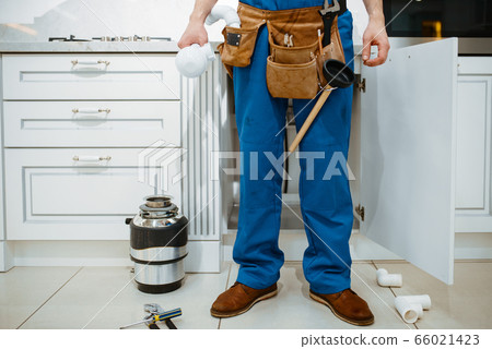 Male plumber installing water filter in kitchen 66021423