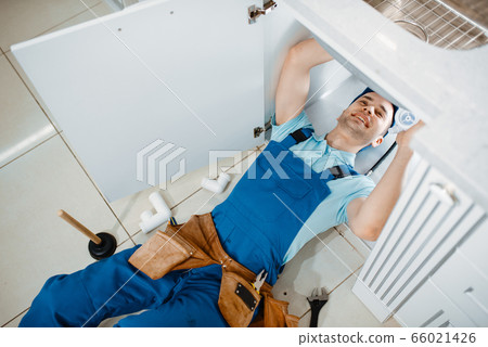 Plumber in uniform installing drain pipe, top view Plumber in uniform installing drain pipe, top view 66021426