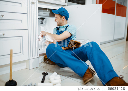 Smiling male plumber in uniform holds drain pipe Smiling male plumber in uniform holds drain pipe 66021428