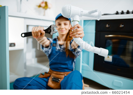 Young female plumber shows wrench and pipe Young female plumber shows wrench and pipe 66021454
