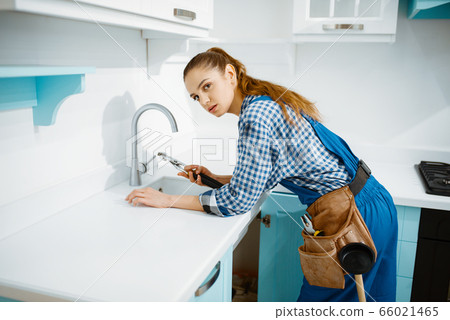 Cute female plumber in uniform fixing faucet 66021465