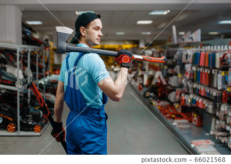 Male worker in uniform holds two axes, tool store 66021568