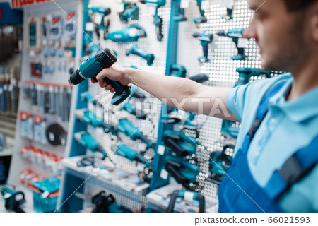 Male worker hand holds electric drill, tool store Male worker hand holds electric drill, tool store 66021593