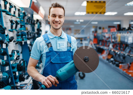 Male worker holds angle grinder in tool store Male worker holds angle grinder in tool store 66021617