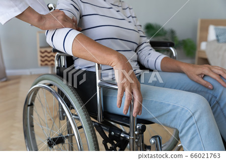 Nurse touch hand of elderly disabled woman in wheelchair closeup Nurse touch hand of elderly disabled woman in wheelchair closeup 66021763