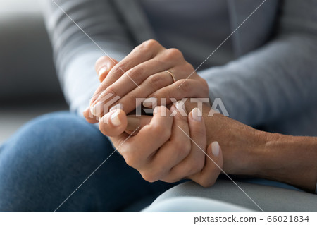 Closeup caring adult daughter holding mothers hand provides psychological support 66021834