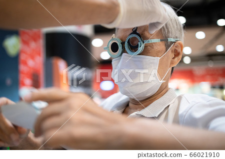 Hand of a male doctor changing lenses in eye testing glasses or trial frame to diagnose senior woman vision,old people eyesight is very bad,prescription glasses by ophthalmologist,elderly eye problems Hand of a male doctor changing lenses in eye testing glasses or trial frame to diagnose senior woman vision,old people eyesight is very bad,prescription glasses by ophthalmologist,elderly eye problems 66021910