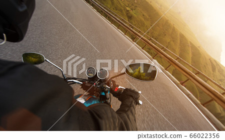 Motorcycle driver riding in Alpine highway, 66022356