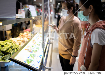Asian female are ordering,buying food in the food court after Coronavirus quarantine or Covid-19 with plastic shield partition between customers and sales people or sellers,social distancing safety Asian female are ordering,buying food in the food court after Coronavirus quarantine or Covid-19 with plastic shield partition between customers and sales people or sellers,social distancing safety 66022983