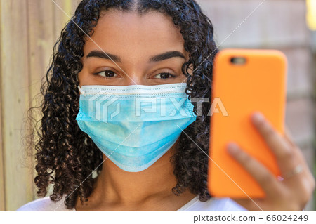 Mixed Race Teenager Girl Woman Wearing Face Mask Using Cell Phone for Socail Media or Selfie Mixed Race Teenager Girl Woman Wearing Face Mask Using Cell Phone for Socail Media or Selfie 66024249