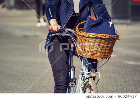 A girl rides a bicycle along a city street, with a A girl rides a bicycle along a city street, with a 66024417