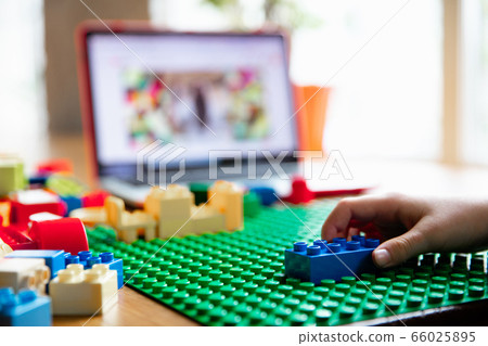 Girl playing with constructor at home, watching teacher's tutorial on laptop. Digitalization, remote education 66025895