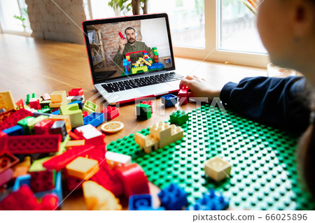 Girl playing with constructor at home, watching teacher's tutorial on laptop. Digitalization, remote education 66025896