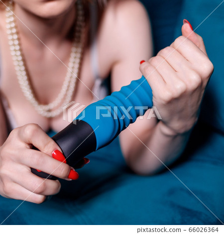 Sexy woman in white lingerie holds pink sex toy on blue couch. Sexy woman in white lingerie holds pink sex toy on blue couch. 66026364