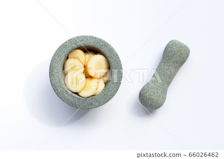 Fresh galangal slices in stone mortar with pestle 66026462